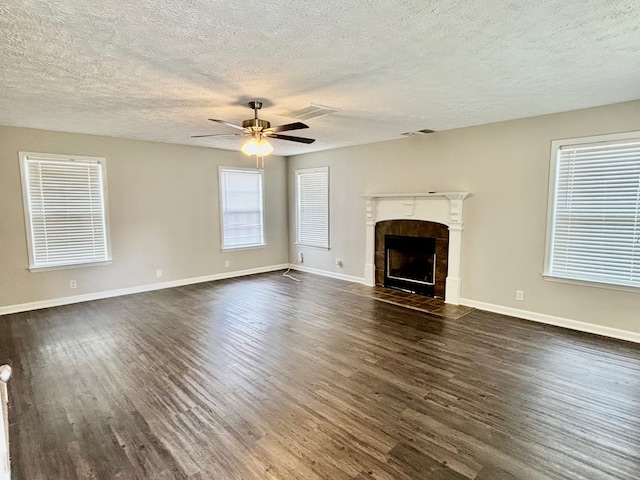 unfurnished living room featuring ceiling fan, a textured ceiling, dark hardwood / wood-style floors, and a tile fireplace