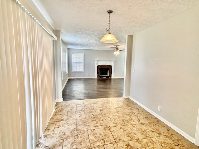 unfurnished living room with ceiling fan, hardwood / wood-style floors, and a textured ceiling