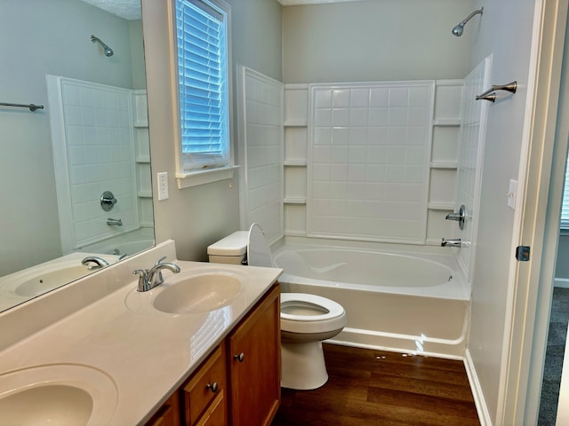 full bathroom with vanity, hardwood / wood-style flooring, washtub / shower combination, and toilet