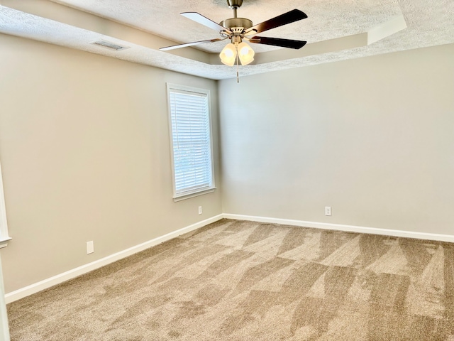 carpeted spare room featuring a textured ceiling, a raised ceiling, and ceiling fan