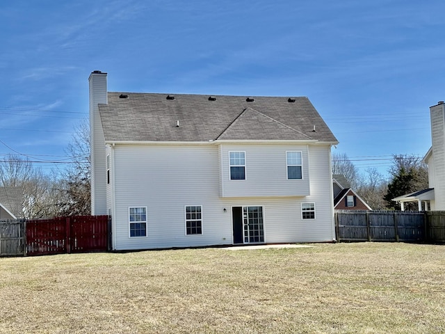 rear view of house with a lawn, a chimney, and fence