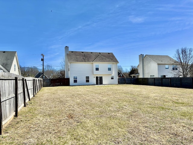 rear view of house featuring a yard and a fenced backyard