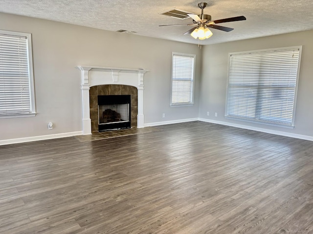 unfurnished living room with baseboards, a ceiling fan, dark wood-type flooring, and a tile fireplace