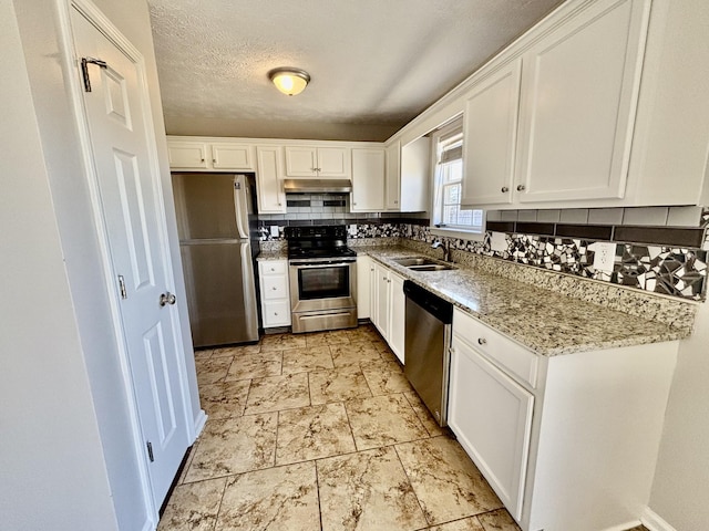 kitchen with backsplash, appliances with stainless steel finishes, white cabinets, a sink, and under cabinet range hood