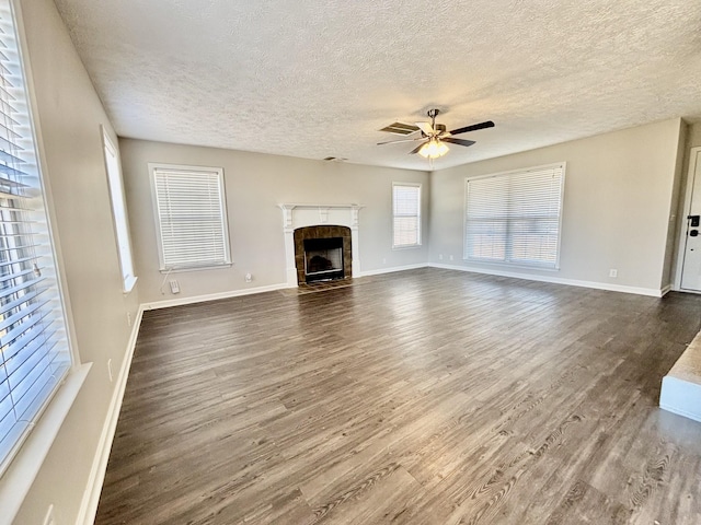 unfurnished living room featuring baseboards, dark wood finished floors, a ceiling fan, a textured ceiling, and a fireplace