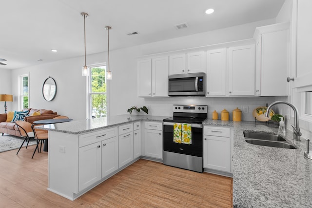 kitchen with hanging light fixtures, sink, light hardwood / wood-style flooring, white cabinetry, and stainless steel appliances