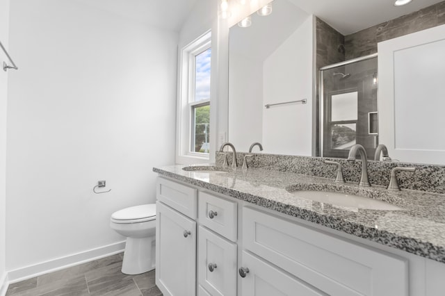 bathroom featuring a shower with door, vanity, and toilet