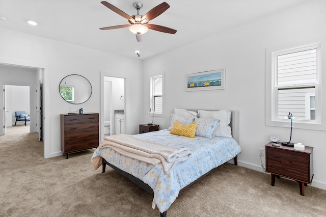 bedroom featuring ensuite bath, ceiling fan, and light colored carpet