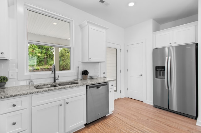 kitchen featuring stainless steel appliances, white cabinets, light wood-type flooring, and sink