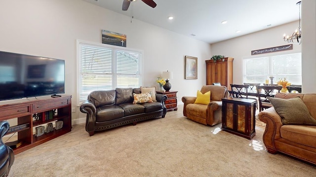 carpeted living room with ceiling fan with notable chandelier