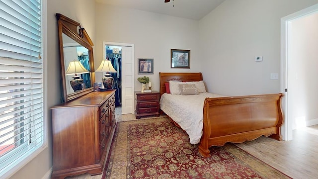 bedroom with a spacious closet, a closet, light hardwood / wood-style floors, and vaulted ceiling