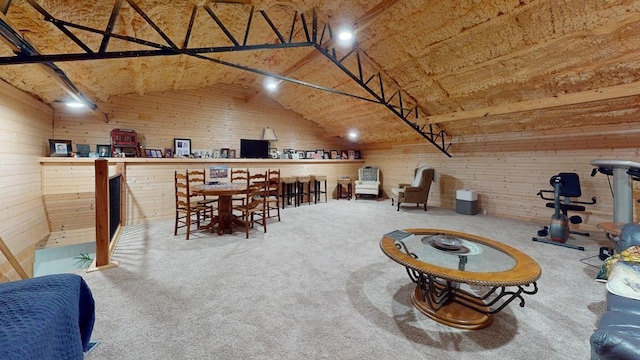 carpeted dining room with lofted ceiling and wood walls