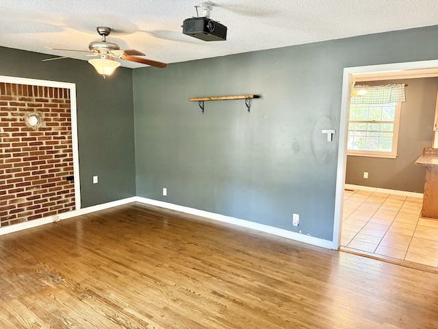 unfurnished room featuring a textured ceiling, ceiling fan, and light hardwood / wood-style flooring