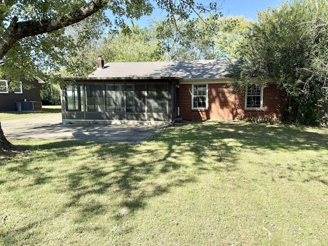 back of property featuring a lawn, a sunroom, and central AC unit