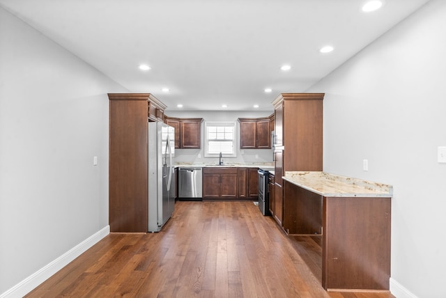 kitchen with light stone countertops, sink, appliances with stainless steel finishes, and dark wood-type flooring