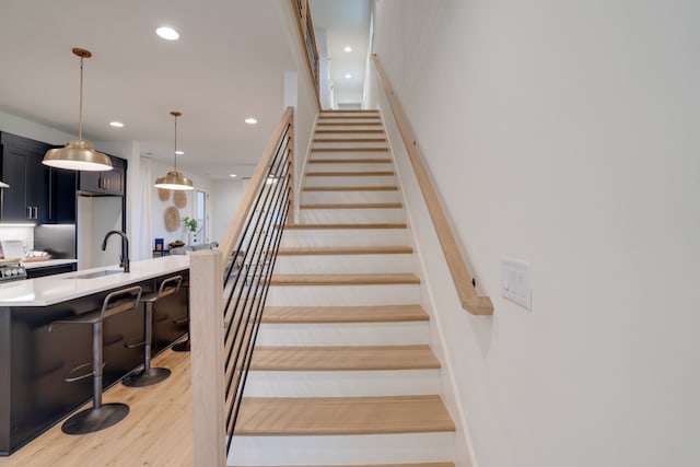 staircase featuring hardwood / wood-style floors and sink