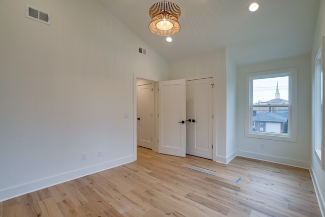 unfurnished bedroom featuring high vaulted ceiling and light hardwood / wood-style floors