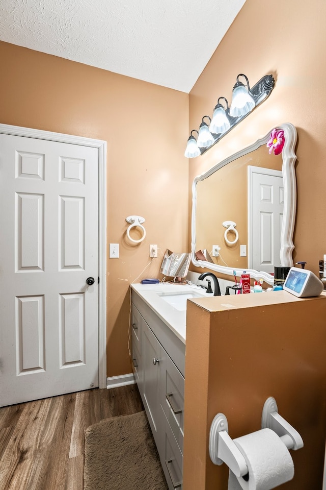 bathroom with a textured ceiling, vanity, and hardwood / wood-style floors