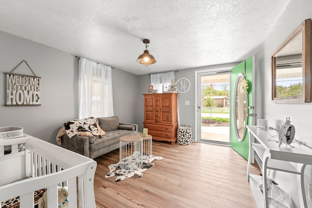 bedroom with light wood-type flooring, a textured ceiling, and access to exterior