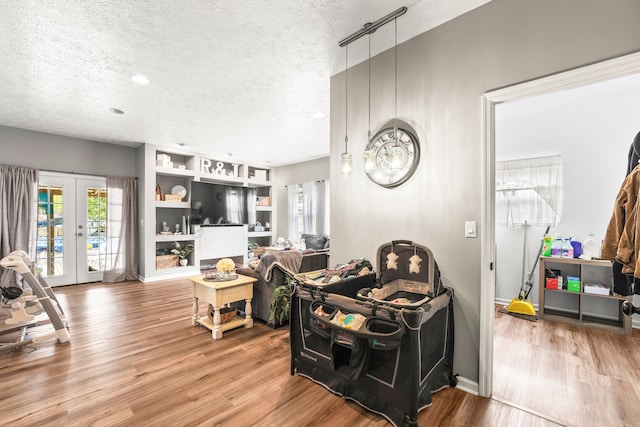 interior space featuring a textured ceiling, hardwood / wood-style floors, built in features, and french doors