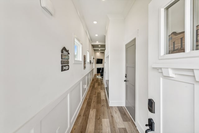 hallway with crown molding and light hardwood / wood-style flooring