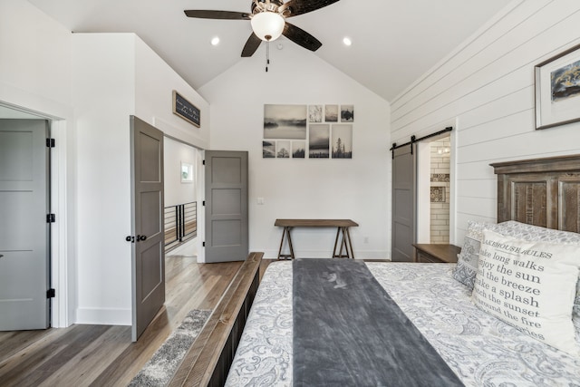 bedroom with high vaulted ceiling, a barn door, ceiling fan, hardwood / wood-style flooring, and ensuite bath