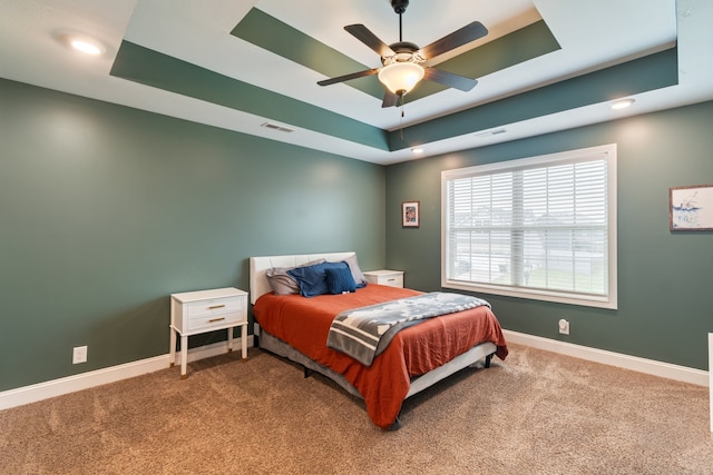 bedroom featuring carpet, a tray ceiling, and ceiling fan