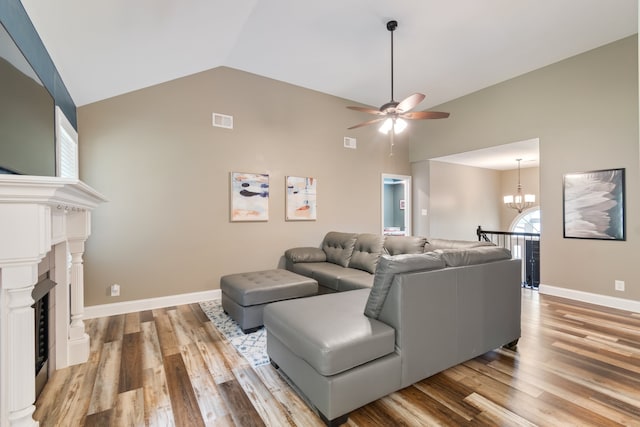 living room with ceiling fan with notable chandelier, wood-type flooring, and vaulted ceiling