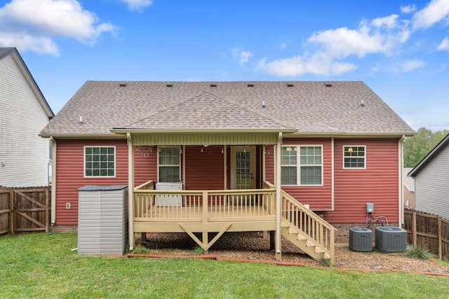 rear view of property with a yard, a deck, and central air condition unit