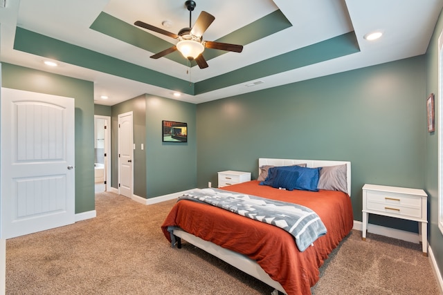 carpeted bedroom featuring ceiling fan and a raised ceiling