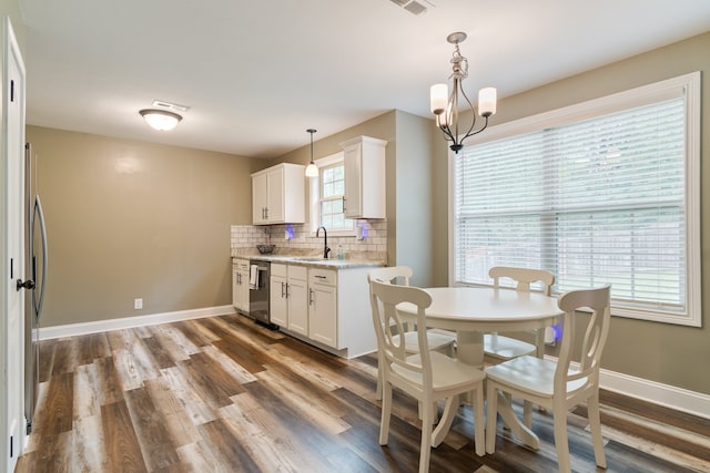 kitchen with decorative backsplash, dark wood-type flooring, white cabinets, light stone countertops, and pendant lighting