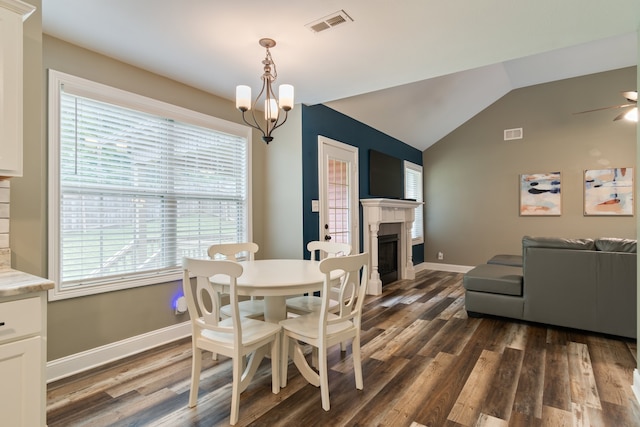 dining room featuring ceiling fan with notable chandelier, lofted ceiling, and dark hardwood / wood-style flooring