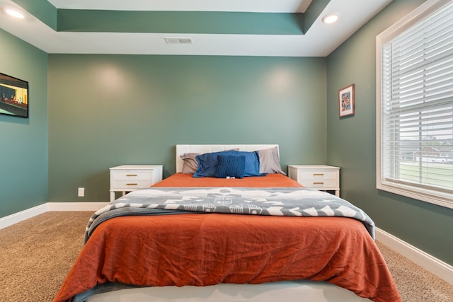 bedroom with carpet flooring and a tray ceiling