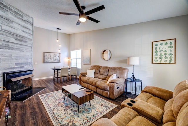 living room featuring a textured ceiling, a multi sided fireplace, ceiling fan, and dark hardwood / wood-style flooring