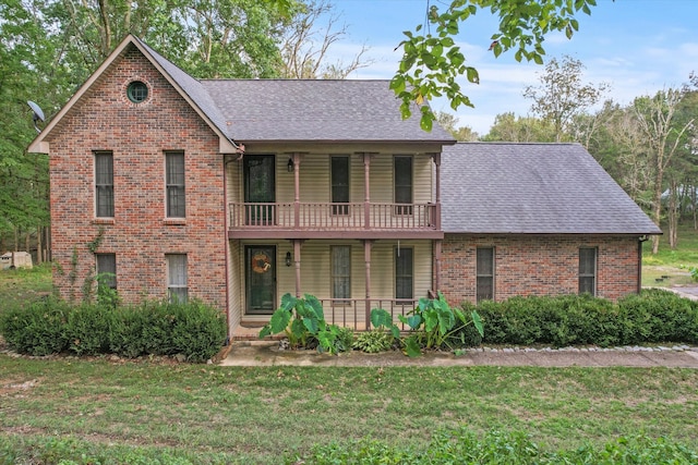 view of property with a balcony and a front lawn