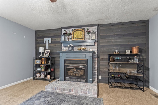 carpeted living room with a textured ceiling, a fireplace, and wood walls