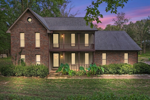 front of property featuring a balcony and a yard