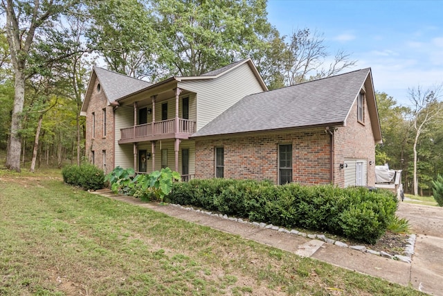 view of side of property featuring a balcony, a yard, and a garage