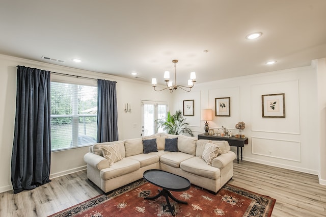 living room with light wood-type flooring, a chandelier, and crown molding