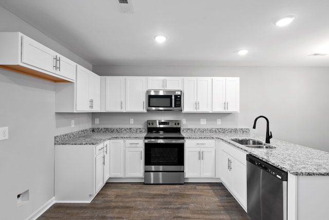 kitchen with white cabinetry, kitchen peninsula, stainless steel appliances, dark hardwood / wood-style floors, and sink