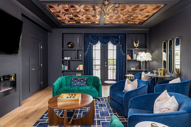 living room featuring built in shelves, hardwood / wood-style flooring, french doors, and ornamental molding