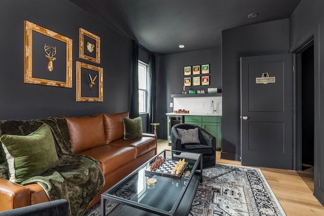 living room featuring wood-type flooring, sink, and wine cooler