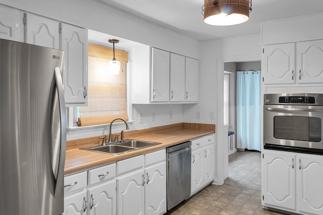 kitchen with white cabinets, stainless steel appliances, hanging light fixtures, and sink