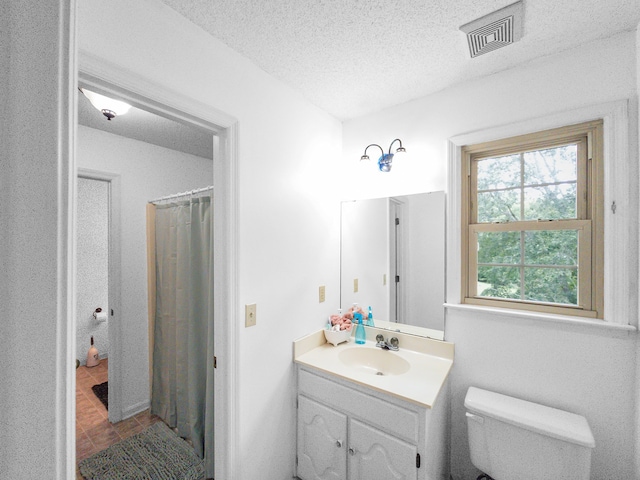 bathroom featuring a textured ceiling, curtained shower, vanity, and toilet