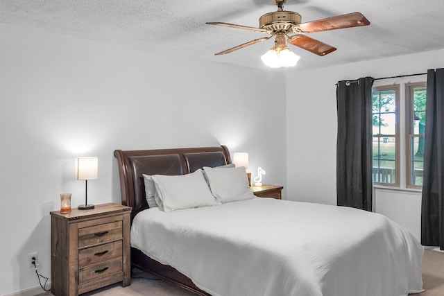 bedroom with ceiling fan, light colored carpet, and a textured ceiling