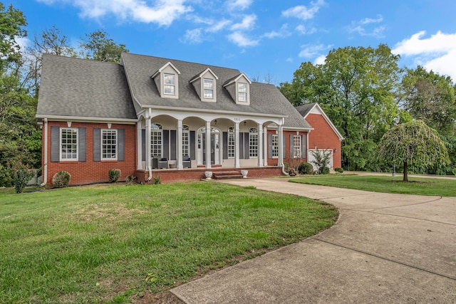 new england style home featuring a porch and a front lawn