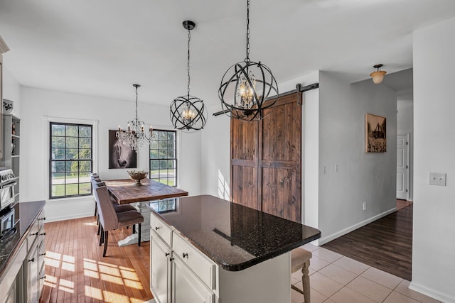 kitchen featuring light hardwood / wood-style floors, white cabinets, hanging light fixtures, a kitchen island, and a barn door