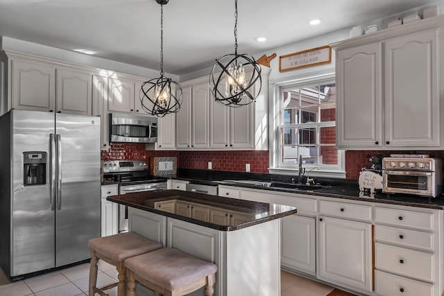 kitchen with decorative light fixtures, appliances with stainless steel finishes, light tile patterned floors, and a kitchen island