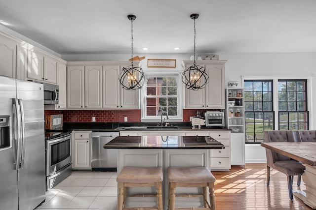 kitchen with decorative light fixtures, stainless steel appliances, and white cabinetry