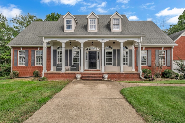 cape cod home with covered porch and a front yard